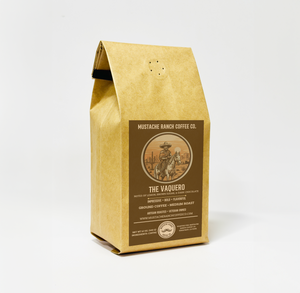 Mustache Ranch Coffee Co. The Vaquero medium roast coffee in a kraft paper bag with a cowboy horse rider illustration and western-style branding on a white background.
