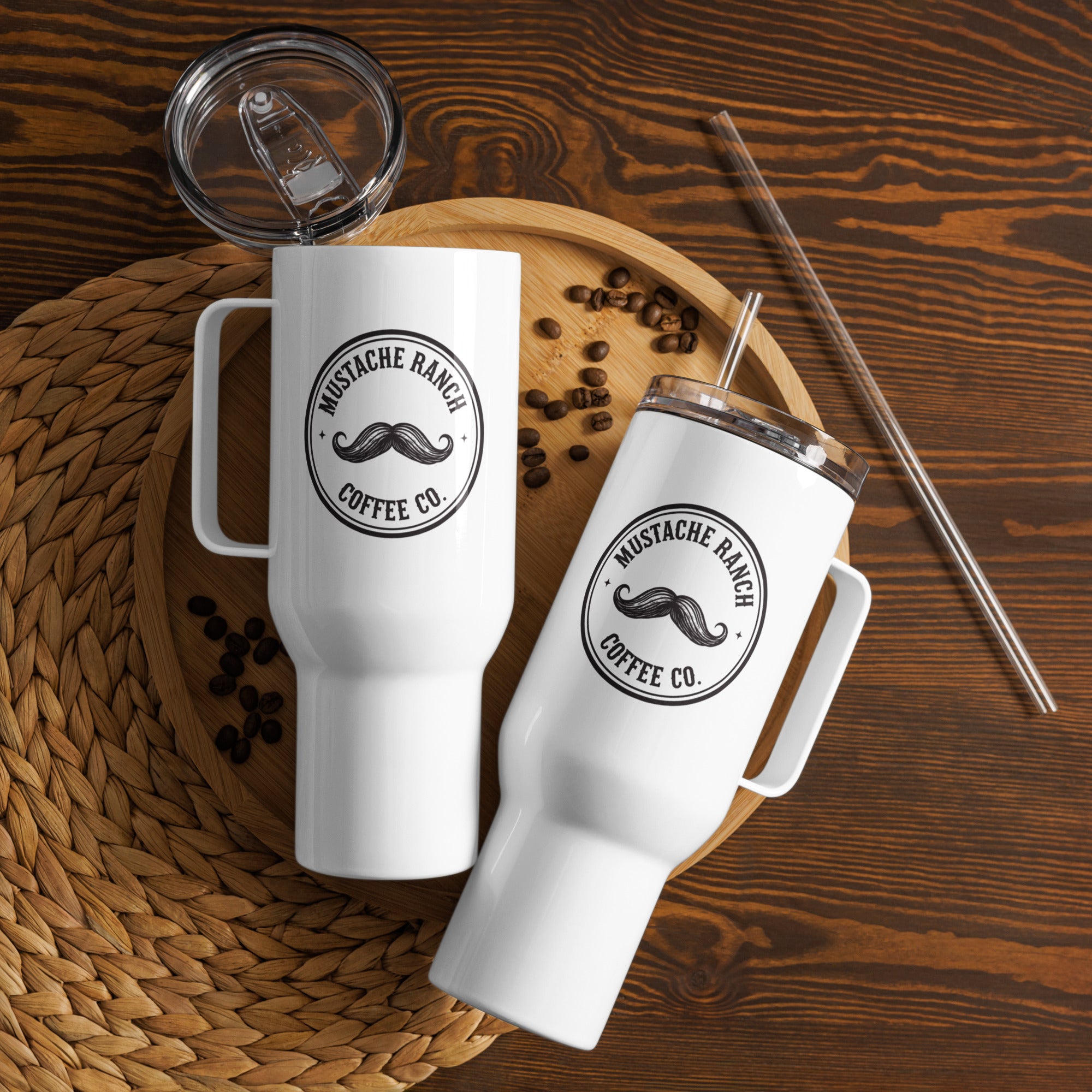 Two white 40 oz. Mustache Ranch Coffee Co. travel mugs with handles and lids arranged on a wooden tray with coffee beans and a reusable straw, styled for a rustic farmhouse aesthetic.